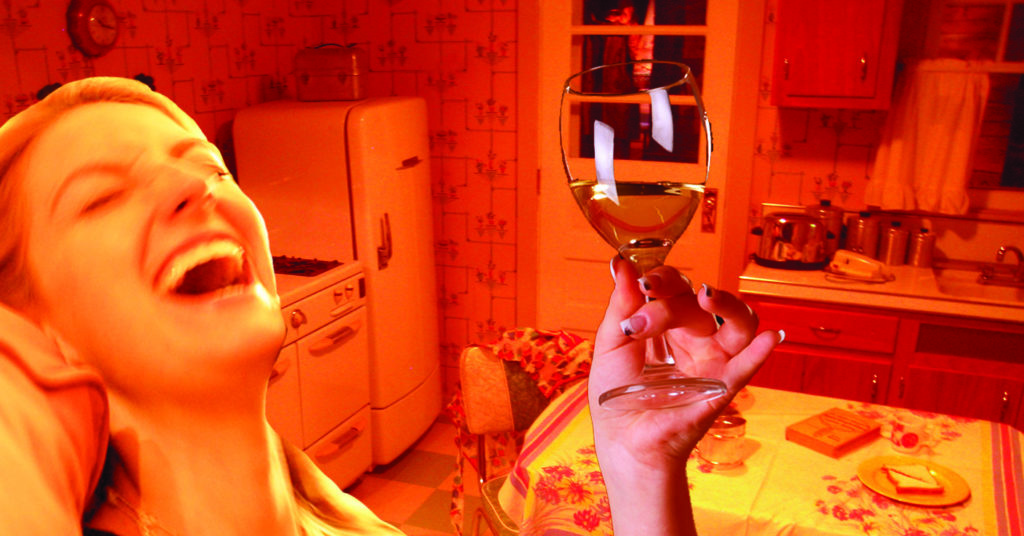 mom laughing with wine glass in kitchen